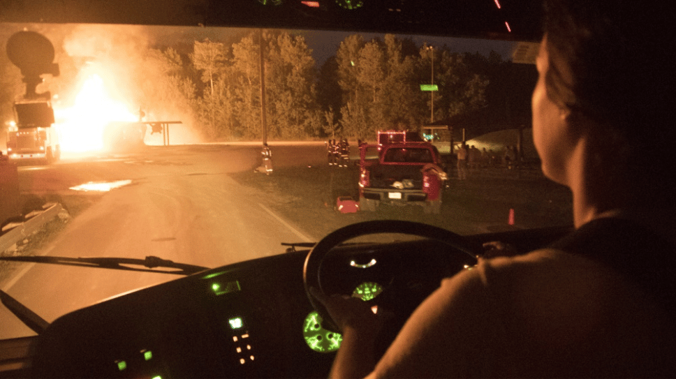 Firefighter driving a firetruck towards a fire.