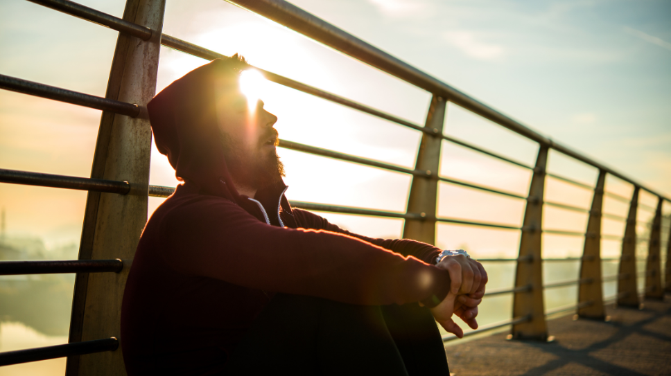 Man on bridge at sunset contemplating life